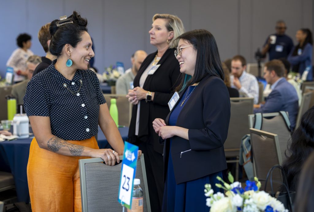 Two communicators standing near their table talking during a break at the summit