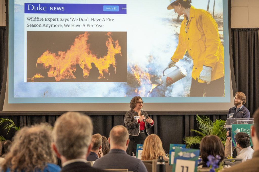 Kirsten Khire and Fedor Kossakovski present on stage in front of a projection of a news story about forest fires