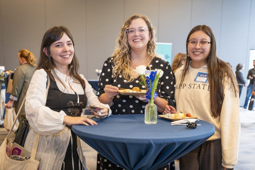 Three communicators standing around the table at the reception